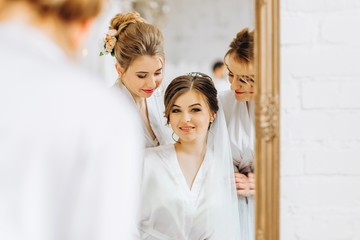 The bride and her friends look in the mirror in their reflection