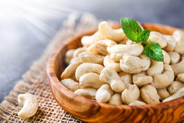 Fresh Cashew nuts in white wooden bowl on black stone table. Delicacies nut on dark background.