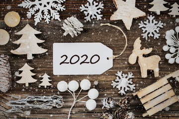 Obraz na płótnie Canvas One White Label With Text 2020. Frame Of Christmas Decoration Like Tree, Sled, Star And Fir Cone. Wooden Background With Snowflakes