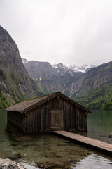 Fototapeta na wymiar Berghütte an einem Bergsee im Gebirge an einem regnerischen wolkigen Tag