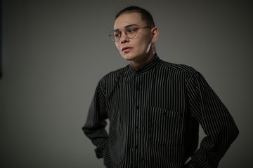 A transgender man in a striped shirt posing