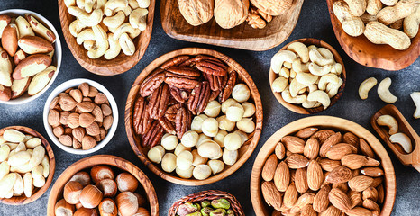 A variety of nuts in wooden bowls from top view. Walnuts, cashew, almond, pistachio, pecan, hazelnut, macadamia nut selection. Healthy super food.