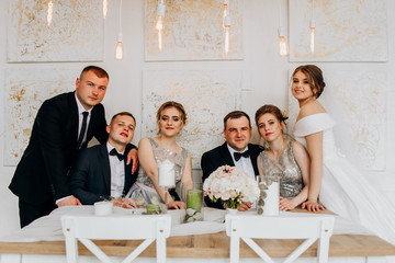 Sweet newlyweds with their friends are sitting at the wedding table