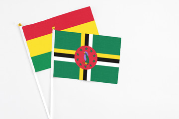 Fototapeta premium Dominica and Bolivia stick flags on white background. High quality fabric, miniature national flag. Peaceful global concept.White floor for copy space.