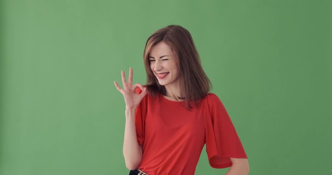Happy young woman giving ok gesture over green background