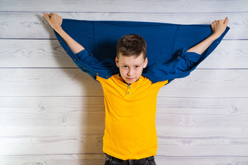 Handsome young boy posing at camera with hands and jacket up at his back. Brunette teen in studio....
