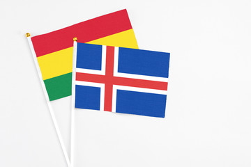 Obraz premium Iceland and Bolivia stick flags on white background. High quality fabric, miniature national flag. Peaceful global concept.White floor for copy space.