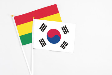 South Korea and Bolivia stick flags on white background. High quality fabric, miniature national flag. Peaceful global concept.White floor for copy space.
