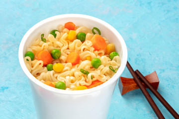 Ramen cup close-up, instant soba noodles in a plastic cup with vegetables, with chopsticks