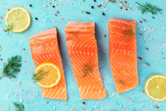 Slices Of Salmon With Lemon And Dill, Overhead Shot With Salt And Pepper On A Blue Background. Cooking Fish, A Flat Lay Composition