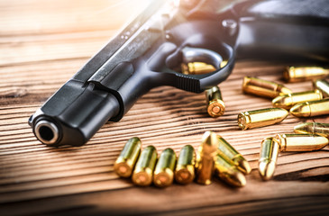 9mm hand gun with bullets on wooden background. Fire pistol and ammunition on table.