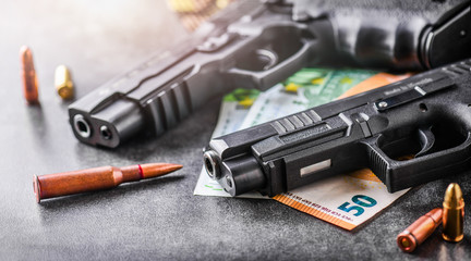 Gun with ammunition and money on stone background. Hand guns weapons concept.