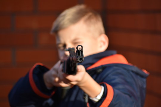 Boy shoots gun. Teenager with gun. Child is learning to shoot from an air rifle.