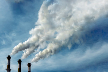 Pipes of an industrial building releasing dirty gray-green smoke into the sky. Air pollution, physiological problem, toxic substances entering the atmosphere