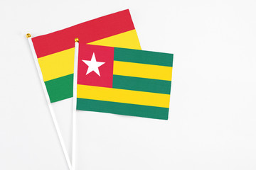 Togo and Bolivia stick flags on white background. High quality fabric, miniature national flag. Peaceful global concept.White floor for copy space.