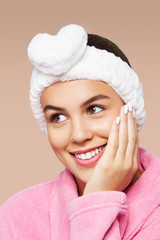 Close-up portrait photo of a dark-haired girl, wearing pink bathrobe and white cosmetic bandage...