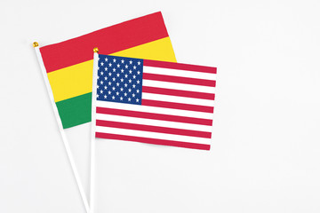 United States and Bolivia stick flags on white background. High quality fabric, miniature national flag. Peaceful global concept.White floor for copy space.