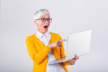 Happy mature middle aged elderly business woman winner excited by reading good news looking at laptop, glad senior older lady watching celebrating online bid bet win or great result victory concept