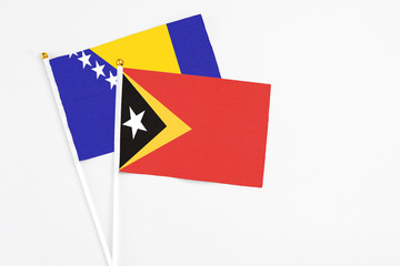 East Timor and Bosnia Herzegovina stick flags on white background. High quality fabric, miniature national flag. Peaceful global concept.White floor for copy space.