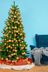 Fototapeta na wymiar Holiday interior. Beautiful decorated christmas tree with blue armchair