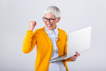 Portrait of a cheerful mature woman with a laptop computer and celebrating success isolated over...