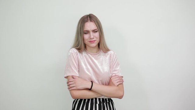 Boring young caucasian woman posing isolated on white background in studio wearing casual shirt, keeping hand on head, headache