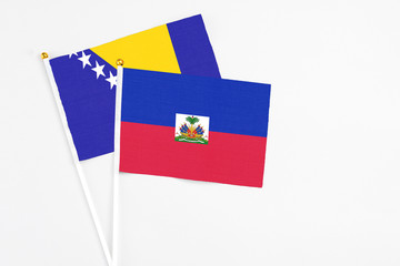 Haiti and Bosnia Herzegovina stick flags on white background. High quality fabric, miniature national flag. Peaceful global concept.White floor for copy space.
