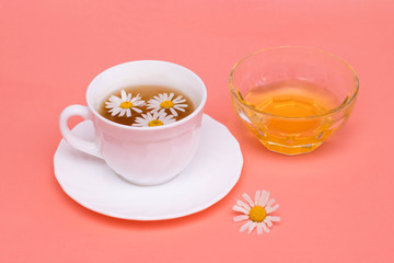 Chamomile tea in a white tea cup, chamomile flowers and honey.