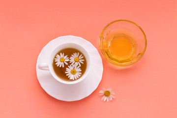 Chamomile tea in a white tea cup, chamomile flowers and honey.