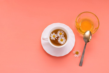 Chamomile tea in a white tea cup, chamomile flowers and honey.