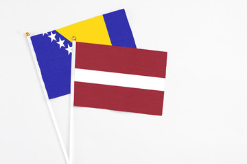 Latvia and Bosnia Herzegovina stick flags on white background. High quality fabric, miniature national flag. Peaceful global concept.White floor for copy space.