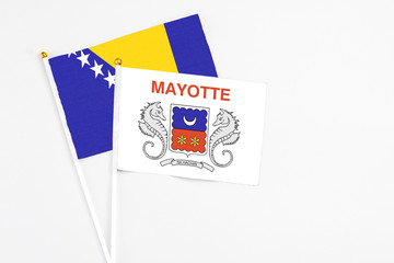 Mayotte and Bosnia Herzegovina stick flags on white background. High quality fabric, miniature national flag. Peaceful global concept.White floor for copy space.