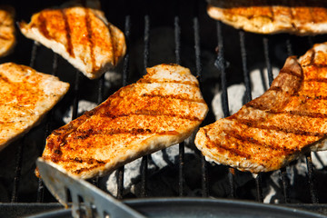 Grilling steaks on barbecue grill.Flaming charcoal grill with open fire. Concept of summer grilling, barbecue, bbq and party. Preparing homemade meal.