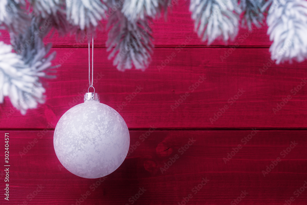 Wall mural Christmas bauble on spruce frosty brunches against red wooden background