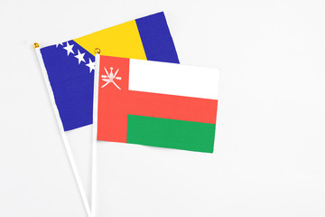 Oman and Bosnia Herzegovina stick flags on white background. High quality fabric, miniature national flag. Peaceful global concept.White floor for copy space.
