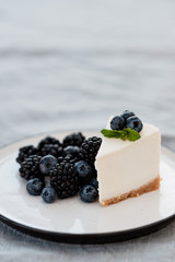 slice of cheesecake with blueberries and blackberries on a gray background. Minimalism
