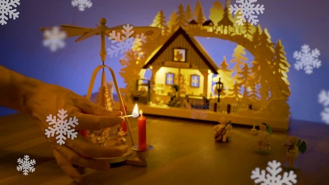 1. Advent, eine Kerze einer Weihnachts Pyramide wird angez&uuml;ndet mit Schwippbogen und Schnee Flocken