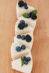 sliced cheesecake in portions with blackberries and blueberries on a wooden board. home food concept. home food concept.
