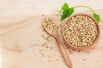 Raw green unprocessed buckwheat on a wooden table in a plate, top view. Copy space, space for text, flat lay