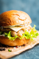 Fresh tasty burgers with roasted turkey cutlet, salad, cheese and different herbs on the rustic background. Selective focus. Shallow depth of field.