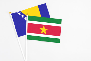 Obraz premium Suriname and Bosnia Herzegovina stick flags on white background. High quality fabric, miniature national flag. Peaceful global concept.White floor for copy space.