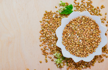 Raw green unprocessed buckwheat on a wooden table in a plate, top view. Copy space, space for text, flat lay