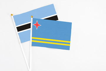 Aruba and Botswana stick flags on white background. High quality fabric, miniature national flag. Peaceful global concept.White floor for copy space.