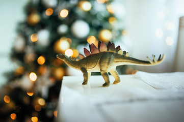 green dinosaur with spikes on the background of a Christmas tree