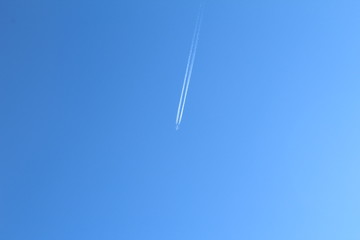 Beautiful picture of white plane flying with trail in blue sky