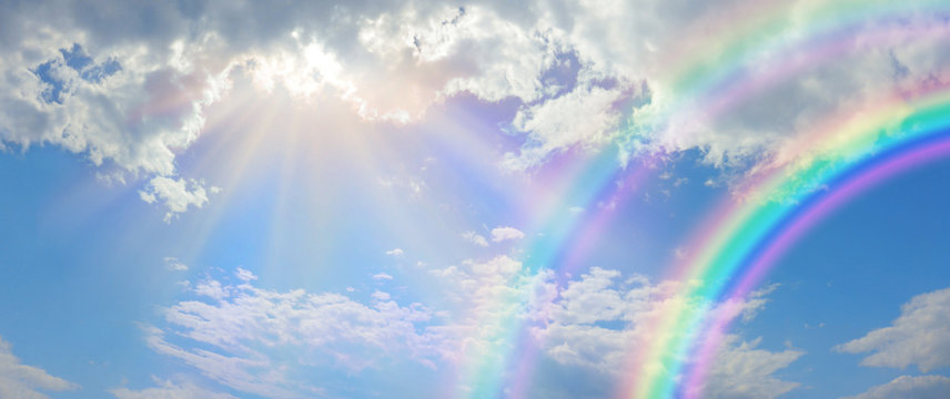 Beautiful vibrant double rainbow Cloudscape Background - awesome blue sky with pretty clouds, bright sun shining down and a large double rainbow arcing across the right corner with copy space