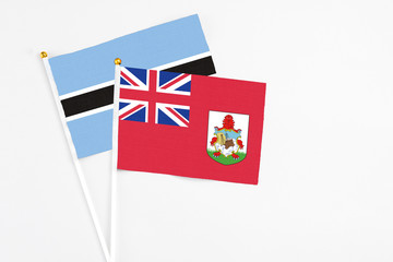 Fototapeta premium Bermuda and Botswana stick flags on white background. High quality fabric, miniature national flag. Peaceful global concept.White floor for copy space.