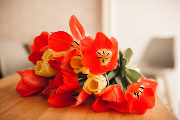 large bouquet of red and yellow tulips on a wooden table in the kitchen