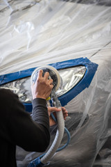 Réparation et Ponçage d'un phare de voiture dans un garage © lamurebenjamin