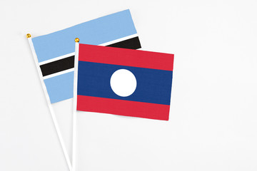 Laos and Botswana stick flags on white background. High quality fabric, miniature national flag. Peaceful global concept.White floor for copy space.